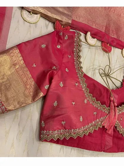 The back of the red blouse, featuring a zig-zag cutwork design, paired with the elegant off-white and red silk saree.