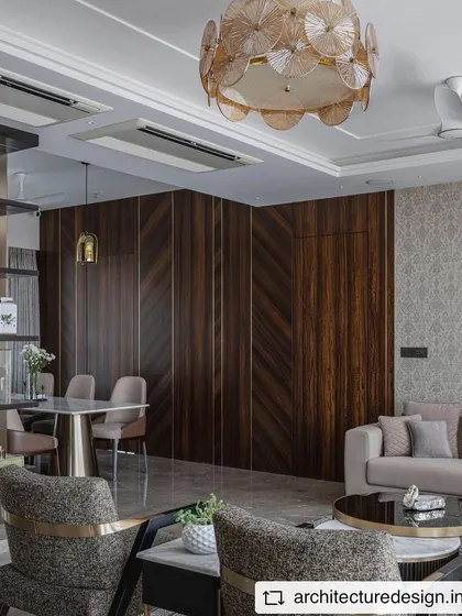 A view of the 'Aria Residence' living and dining area, showing the dark veneer wall paneling that adds depth and richness to the space. The open layout creates a seamless flow between the two zones.