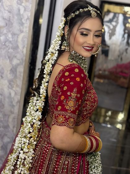 This side profile showcases the stunning floral hair accessory woven into her braid, adding a touch of modern romance to her classic red bridal attire.
