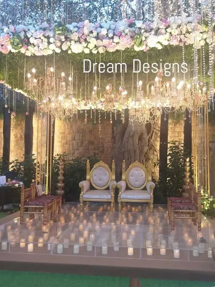 A truly magical mandap setup. The structure is topped with a dense arrangement of flowers, with crystal chandeliers and candles on the floor creating a warm, ethereal glow from every direction.