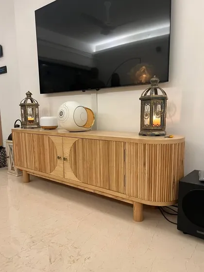 A custom media console built from solid ash wood, featuring rounded edges and fluted door details. This piece combines ample storage with a sophisticated Scandinavian-inspired aesthetic for a stylish living area.