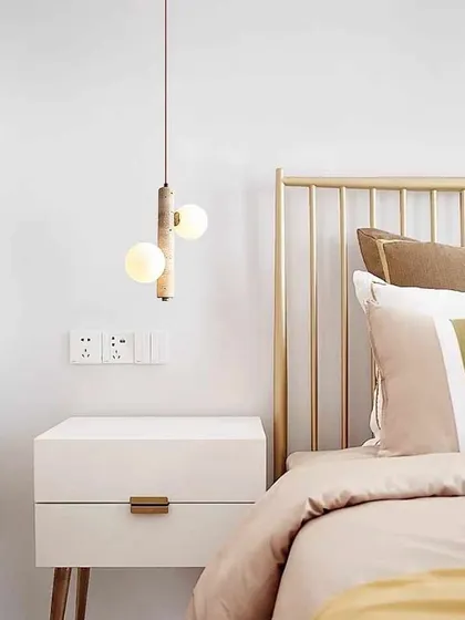 A minimalist pendant with a wooden element and two frosted globes, installed as a bedside light. The mix of materials adds warmth and texture.