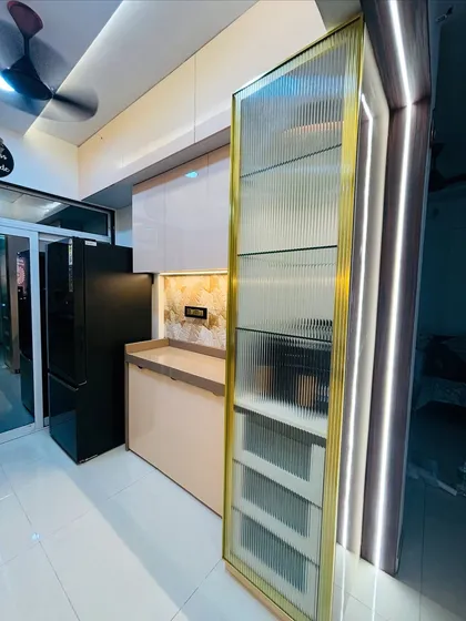 A close-up of a custom storage solution. This tall pantry unit features a ribbed glass shutter with a brass-finished frame, providing elegant and accessible storage for kitchen essentials.