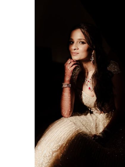 A stunning portrait of the bride. The soft lighting beautifully illuminates her shimmering lehenga and elegant jewelry, capturing her radiance.