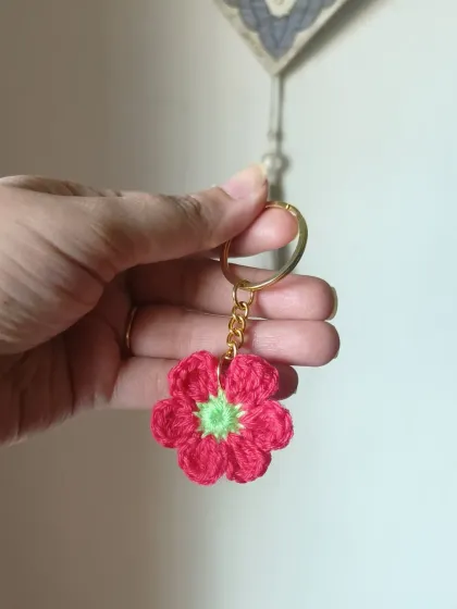 This red floral keychain has a bright green center, creating a vibrant and eye-catching color contrast.