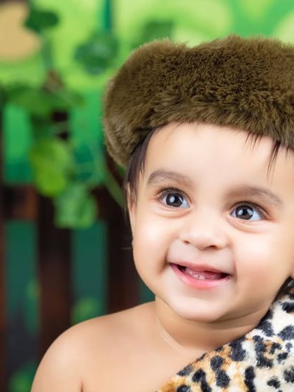 A close-up of a smiling baby boy in his jungle explorer outfit. His happy expression says it all.