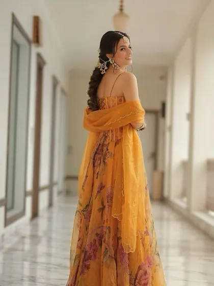 A full-length shot of the bride with her beautiful floral braid. The hairstyle complements her yellow floral outfit perfectly, making it an ideal look for a Haldi or Mehendi ceremony.