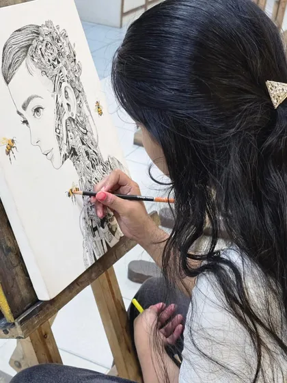 A close-up view of the artist's hand as she adds more intricate mechanical parts to her biomechanical portrait with a fine-tipped micron pen.