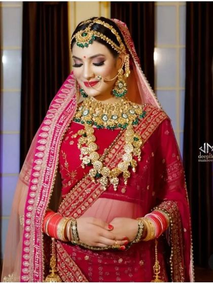 A regal bride with her hair in a classic bun, perfectly styled to accommodate a heavy dupatta and elaborate jewelry. This look is fit for a royal wedding.