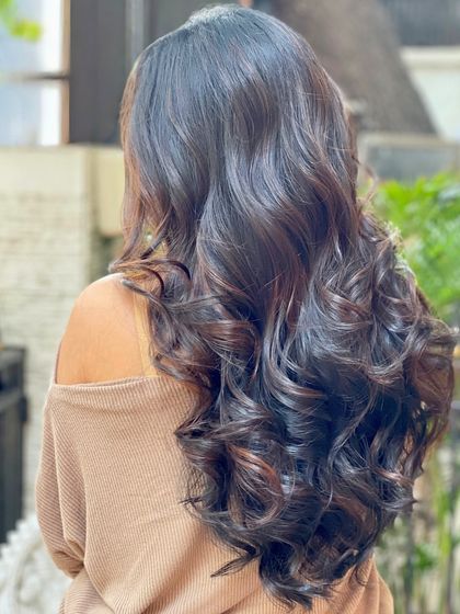 The deep, luscious curls of a Coffee Brown Balayage. The styling enhances the multi-tonal effect of the colour, making it look even richer.