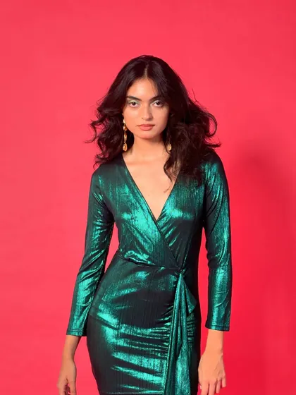 A head-on shot that showcases the deep V-neckline and wrap detail of the metallic dress, a perfect example of modern party wear.