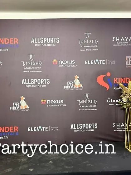 We create custom-printed backdrops that prominently feature event sponsors and partners. This step-and-repeat banner is framed with elegant gold and white floral arrangements for a polished look.