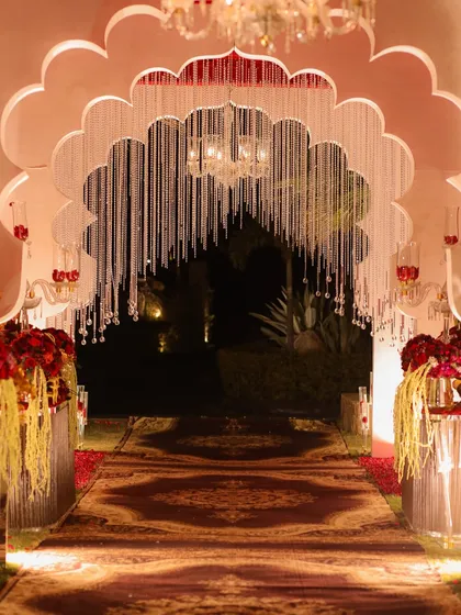 The grand entrance to the wedding, featuring a scalloped arch with hanging crystal strings. This sets a majestic tone, leading guests down a custom-printed carpet to the main event.