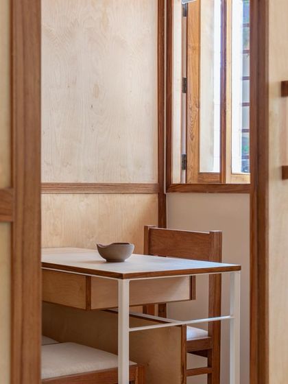 A view through a doorway reveals the minimalist and functional design of the consultation room, with its custom-built desk and chair.