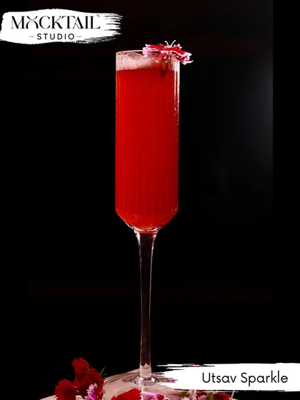 The "Utsav Sparkle," a vibrant red mocktail served in a tall champagne flute. Its elegant presentation and festive color make it a perfect non-alcoholic option for any celebration.