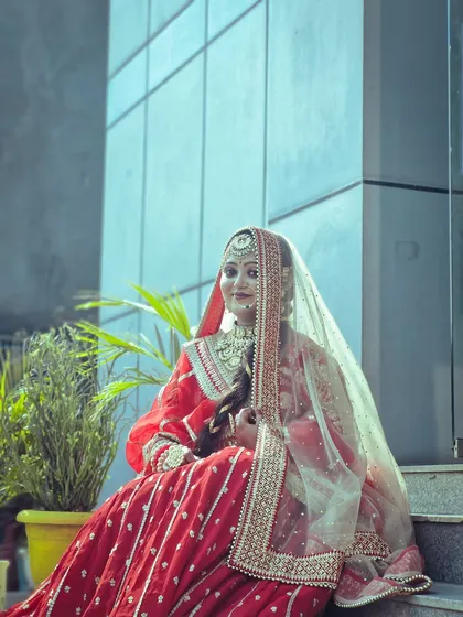 This student's creation features a beautiful red bridal outfit with a sheer, embellished dupatta. The makeup is kept timeless and elegant to match the overall aesthetic.