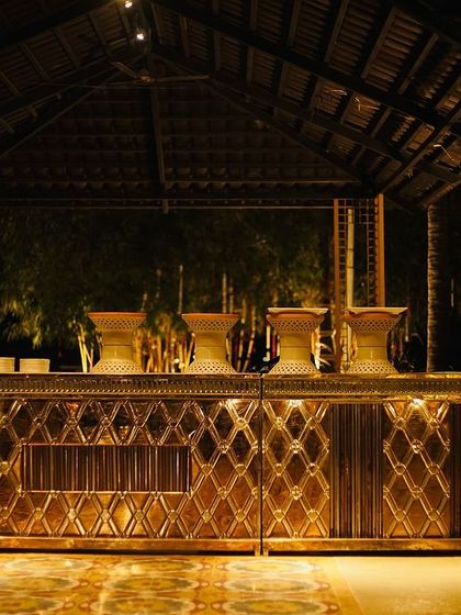 A beautifully crafted wooden and brass bar counter for an evening event. The intricate design and warm lighting create a premium and inviting space for serving drinks and starters.