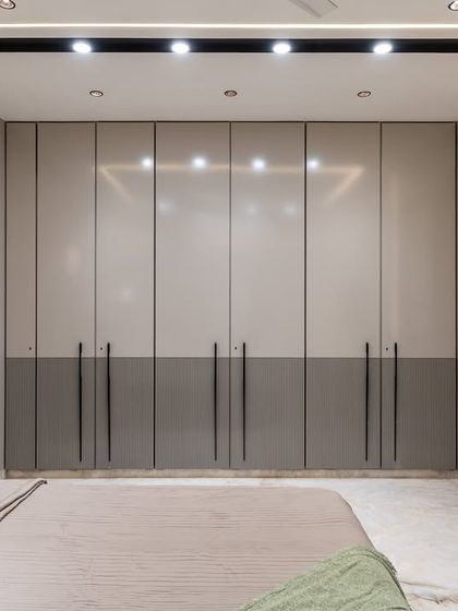 Where texture tells a story. This bedroom brings depth and drama with a bold black-veined marble accent wall that feels like nature’s own art. Balanced with soft taupes, warm beiges, and mirror detailing on the wardrobe shutters, the space becomes a sanctuary of contrast and calm.