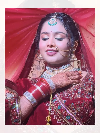 A classic pose under the red dupatta. The golden shimmer on her eyes and the rich color of her lehenga create a look that is both royal and romantic.