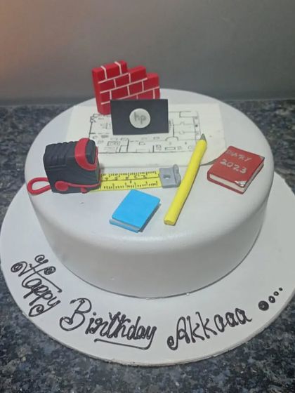 An architect-themed cake featuring edible blueprints, a measuring tape, bricks, and other tools of the trade. A creative way to celebrate a builder or designer.