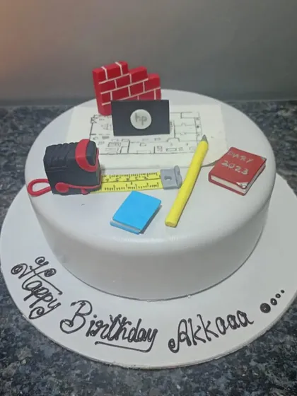 A custom cake designed for an architect. It features a blueprint, measuring tape, bricks, and other tools of the trade, all completely edible.