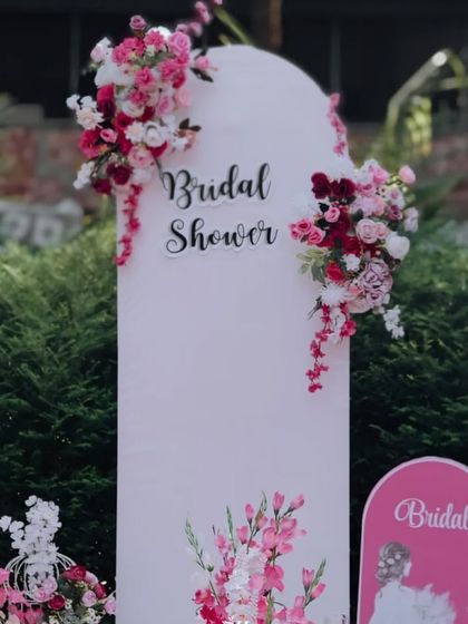 A beautiful and elegant bridal shower backdrop with cascading floral arrangements in shades of pink and white.