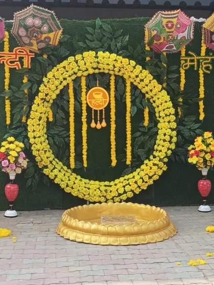 A beautiful outdoor Haldi and Mehandi setup against a green foliage wall. The large marigold ring and traditional urli create a classic and elegant look for the ceremony.
