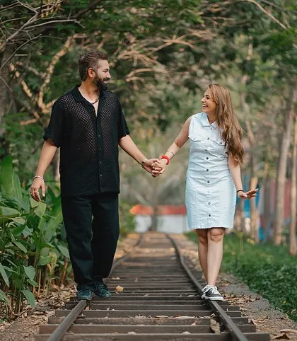 Nishant and Jaspal walk hand-in-hand along the railway tracks, sharing a smile. This candid shot captures a simple, happy moment on their journey together.