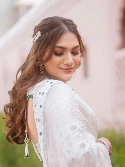 A side profile of the bride's Mayra look, showing her soft waves and a delicate hair accessory. The look is understated and elegant.