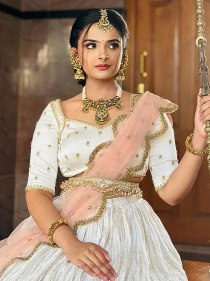 Another view of the bride in her white and peach half-saree, looking radiant and happy.