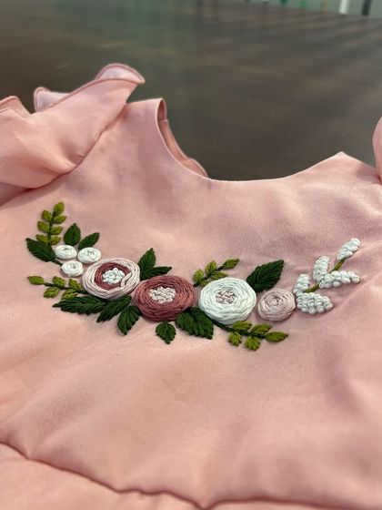 Delicate flower blossoms hand-embroidered with thread, brightening up a lovely pink top for a little one.