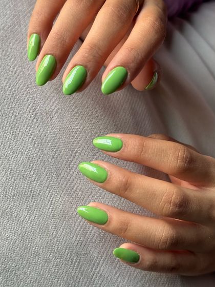 A fresh and vibrant set of solid green nails in a classic almond shape.