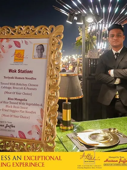 Witness an exceptional catering experience at our Wok Station. The menu, displayed in an ornate golden frame, offers a variety of choices like Teriyaki Ramen and Riso Mongolia for guests to enjoy.