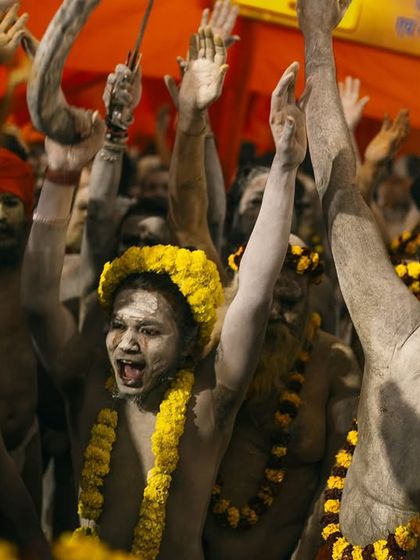 Young Naga sadhus celebrate with their arms raised in the air. Their joyful and energetic expressions show the celebratory side of the Kumbh Mela.