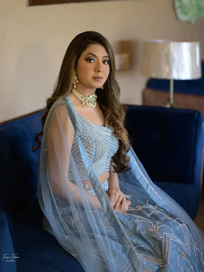 How perfectly color-coordinated is this look? The blue lehenga, the blue sofa, and the soft, neutral makeup all work together beautifully.