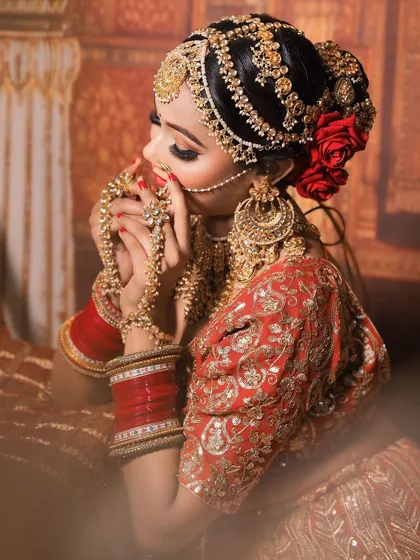 An artistic shot of the bride adjusting her hathphool, giving a great view of the detailed matha patti and hair adornments.
