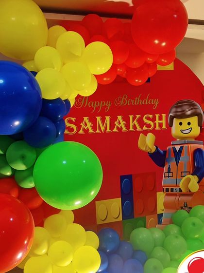 A close-up of a LEGO-themed party, showing a LEGO Emmet cutout against a red backdrop.