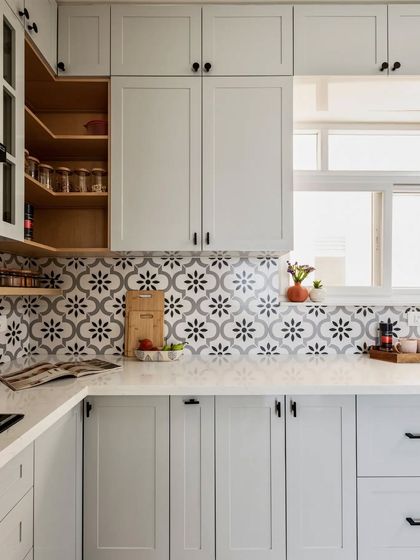 A closer look at the refined neutral kitchen, focusing on the beautiful grey and black patterned tile and the neatly organized open spice racks.
