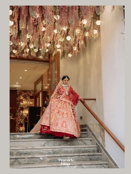 The bride makes a grand entrance down a staircase, under a ceiling of hanging flowers. A truly magical and elegant bridal portrait.