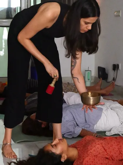 Akanksha uses a singing bowl to help ground the energy in the room during a breathwork session, combining sound and breath for a deeply immersive healing experience.