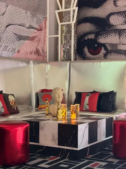 A geometric setting for a cozy lounging corner. The checkerboard coffee table, metallic red stools, and pop-art backdrop made this space both comfortable and incredibly aesthetic. ✨