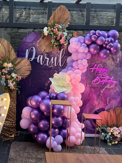 A closer view of the purple-themed 27th birthday decor, showcasing the floral arrangements and neon sign.