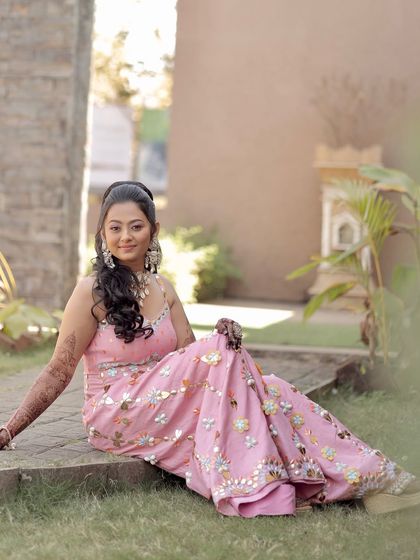 A playful, seated pose that shows off the full, flowing outfit. The pastel makeup adds to the dreamy, carnival-like vibe.