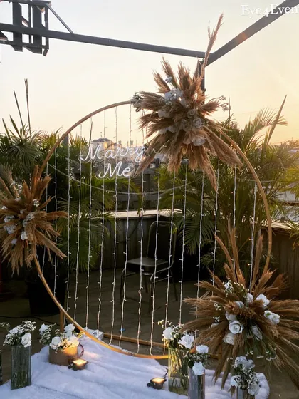 Our boho "Marry Me" setup basking in the golden hour light. The natural textures of the pampas grass combined with the warm glow of the sunset make for an incredibly photogenic proposal spot.