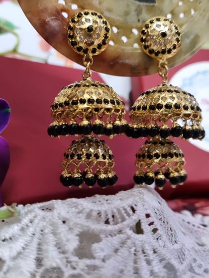 The 'काजल' (Kajal) layered jhumkas with black beads. The black detailing adds a bold and dramatic touch, making them perfect for evening events.