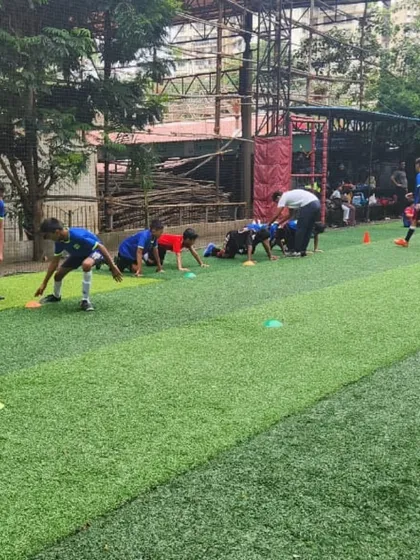 Excellence begins with the fundamentals. Here, one of our expert coaches provides hands-on instruction during a football training drill, focusing on skill development and tactical awareness on an artificial turf pitch.