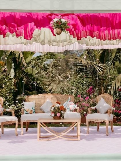 A relaxed lounge area at the Goa Mehendi, with a canopy of ruffled pink and white drapes providing shade and adding to the soft, romantic beach vibe.