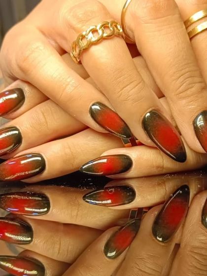 A dramatic red and black ombre cat-eye effect on long, almond-shaped nails.