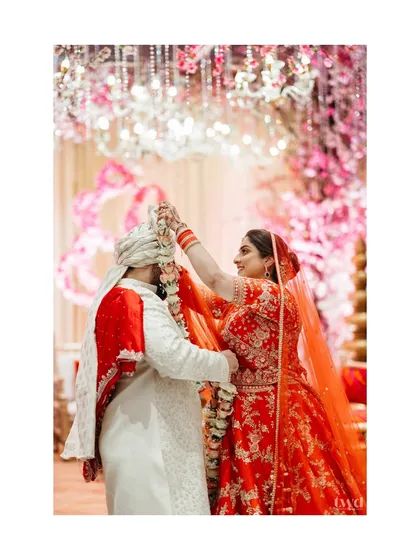 A close-up shot of the bride placing the varmala on the groom. The focus on this single action highlights the significance and beauty of the ritual.