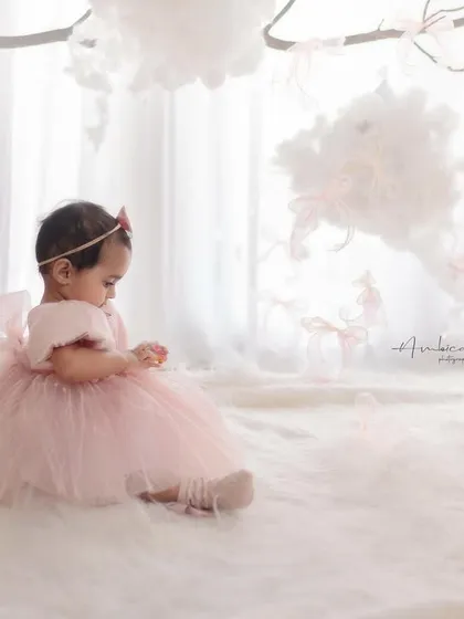 A quiet, contemplative moment amidst the birthday setup. The soft lighting and dreamy atmosphere create a beautiful, painterly portrait.